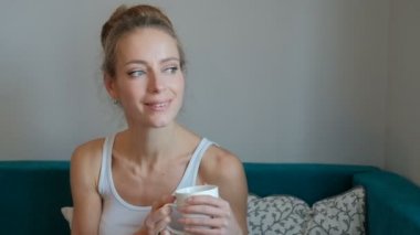 Bir kadın bir fincan tutarak ve ilgi ile bakarak Beyaz gömlekli.