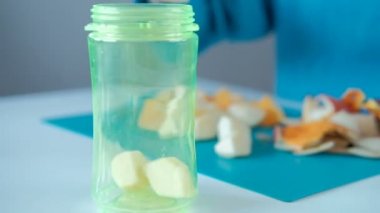 Bir kadın adet meyve smoothies yapmak için bir şişe içine atar..