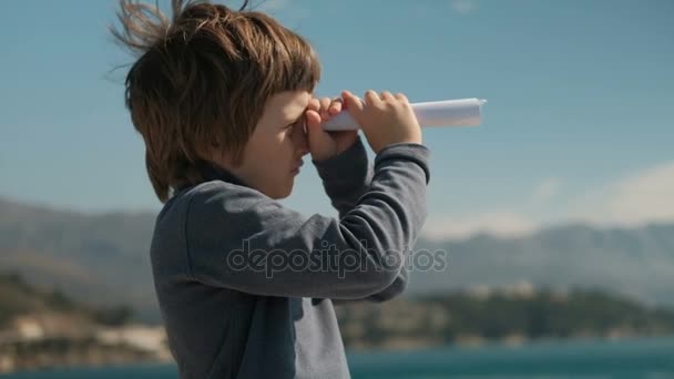 Мальчик складной лист бумаги глядя вдаль труба в горы — стоковое видео