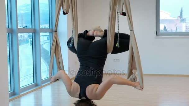 Woman in a hammock doing yoga asana in the lotus position upside down. — Stock Video