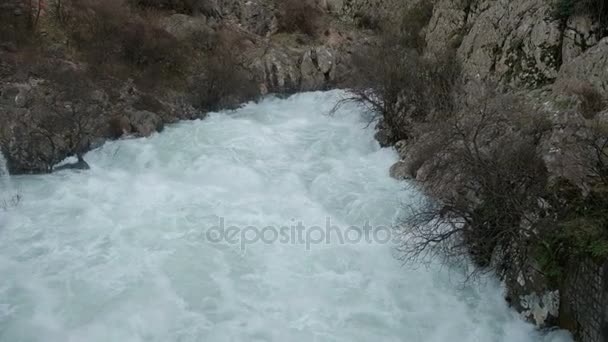 Бушующая горная река широко течет среди гор . — стоковое видео