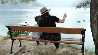 Kadın ve çocuk bakan deniz telefonla fotoğraf çekmeye oturan.
