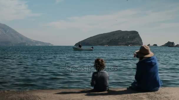 Młoda kobieta i dziecko siedząc na brzegu oceanu. — Wideo stockowe