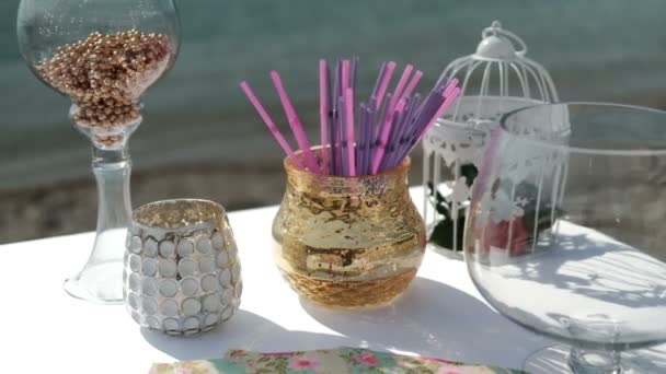 Glasses and vases on table by sand seashore. — Stock Video