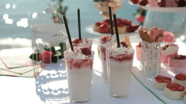 Mesa blanca cargada de dulces manjares se encuentra en la orilla del océano . — Vídeos de Stock