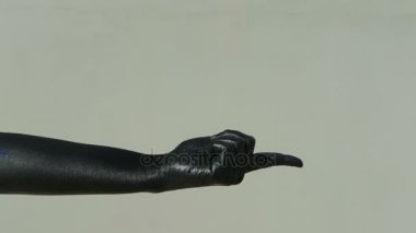 Kara el ile işaret parmağı gri duvara kapalı çağırıyor.