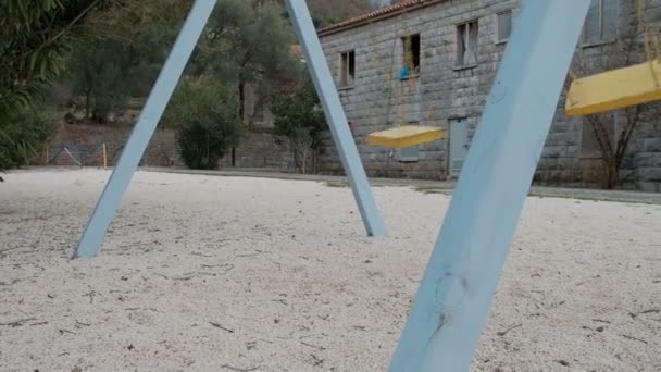 Empty playground with moving swig in winter in Europe. — Stock Video