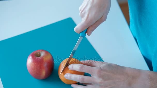Frau schneidet zu Hause frische Orange mit Messer auf dem Brett. — Stockvideo