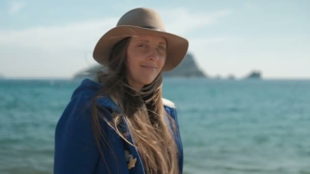 Mladá žena chodí po pláži v klobouku a vypadá na kameru a okolí na mapě. — Stock video