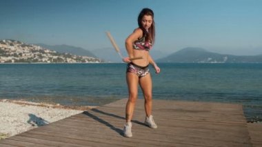 Güzel bir kadın bir deniz iskele üzerinde ustaca ahşap nunchakas döner.