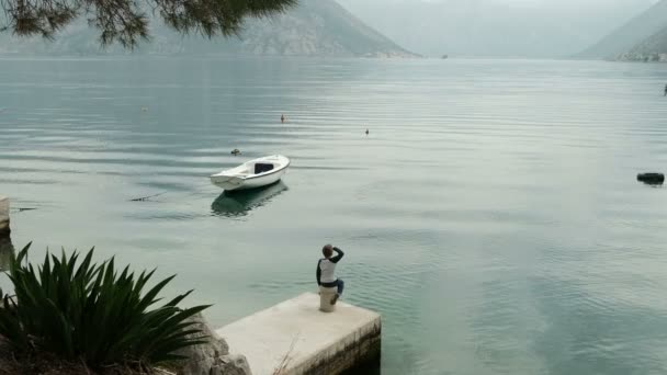 Little boy sitting on pier sea in summer day. — Stock Video