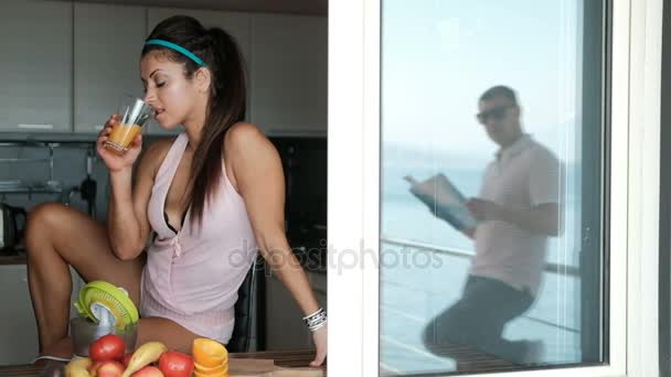 Giovane donna che beve succo di frutta, in posa per il marito davanti alla finestra . — Video Stock