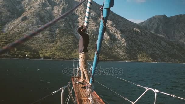 若い男は、帆船の船首斜檣上に立つし、屋外悲鳴. — ストック動画