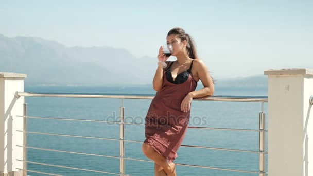 Jeune femme debout sur la loggia et boire du vin à l'extérieur . — Video