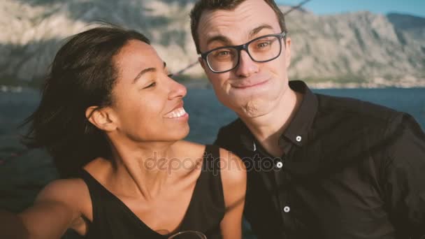 Joven hombre y mujer alegremente haciendo selfie en barco al aire libre . — Vídeos de Stock