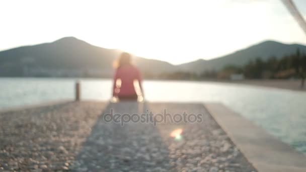 Jonge vrouw zit wat betreft gezicht aard op stenen op rivieroever. — Stockvideo