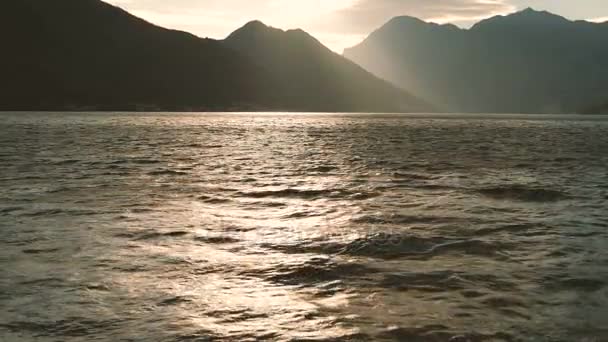 Charmante zonsondergang op een kalme zee met hoge bergen horizon. — Stockvideo