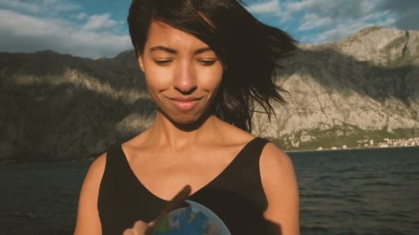 Young lady turns globe standing on ship outdoors. — Stock Video