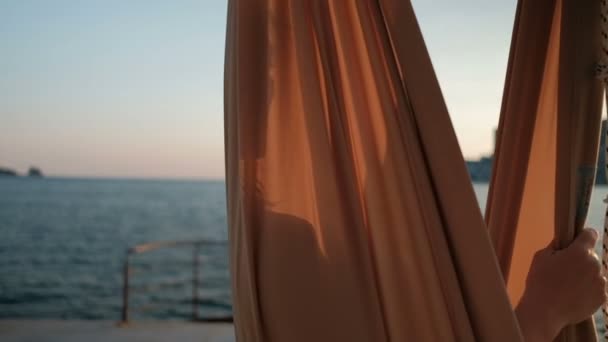 Lachende vrouw die zit op een hangmat aan het meer bij zonsondergang. — Stockvideo