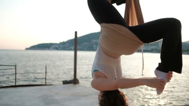 Young woman hanging upside down in hammock on coast outdoors. — Stock Video