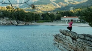 kadın bir bacak ayakta kaya üzerinde denge egzersiz yoga yapar