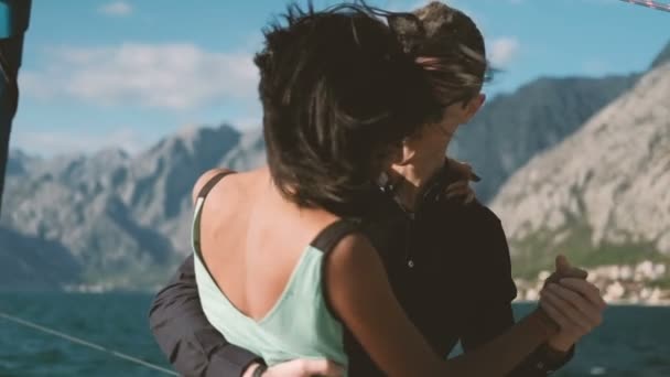 Amanti uomo e donna che ballano lentamente su una costa ventosa. Un appuntamento romantico in viaggio in barca privata . — Video Stock