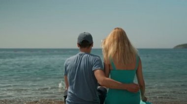 Güneşli günde kıyıda oturan genç Çift.