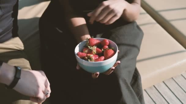 Two young people eat strawberries outdoors. — Stock Video