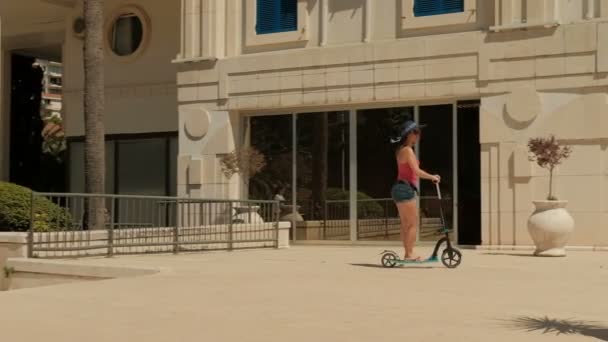 Ung kvinna Rider scooter utomhus på sommardag. — Stockvideo
