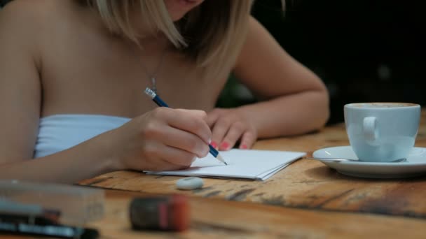 Mujer con una taza de café hace un boceto a lápiz sobre papel . — Vídeos de Stock