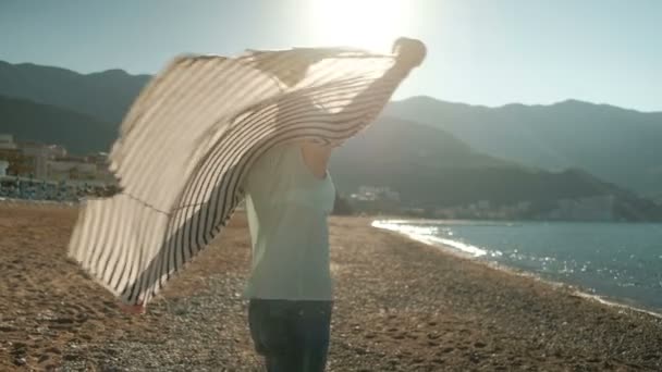 Woman walking on sea shore, looking into distance, wind t-shirt — Stock Video