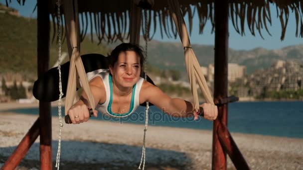 海岸上的女人进行在吊床上姿势瑜伽飞行. — 图库视频影像