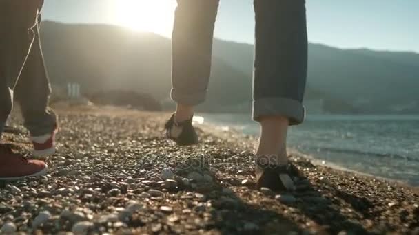 Liebespaar spaziert an sonnigem Tag am steinigen Strand entlang. — Stockvideo