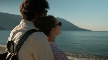 Seven çift sahilde duran ve gün batımını izlemek güneş gözlüğü.