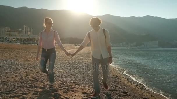Νεαρό ζευγάρι περπάτημα κατά μήκος της ακτής στη θερινή ημέρα. — Αρχείο Βίντεο