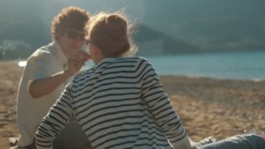 Sevgi dolu çift kumlu sahilde günbatımı üzerinde oturur..