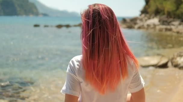 Tourné de dos de fille avec des cheveux rouges orange debout sur le rivage de la rivière — Video