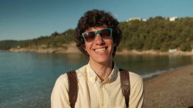 Sahilde şık güneş gözlüğü neşeli kıvırcık erkeklerde portresi.