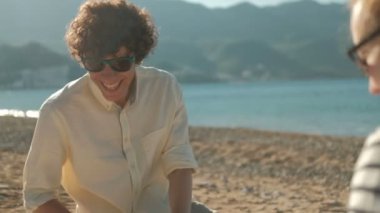 Kumsalda oturuyor ve yaz günde topladıklarıçilekleri kadın ve erkek.