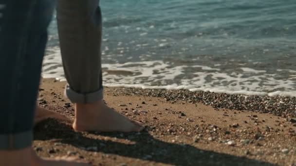 Άνδρας και γυναίκα με γυμνά πόδια περπατώντας κατά μήκος της ακτής στη θερινή ημέρα. — Αρχείο Βίντεο