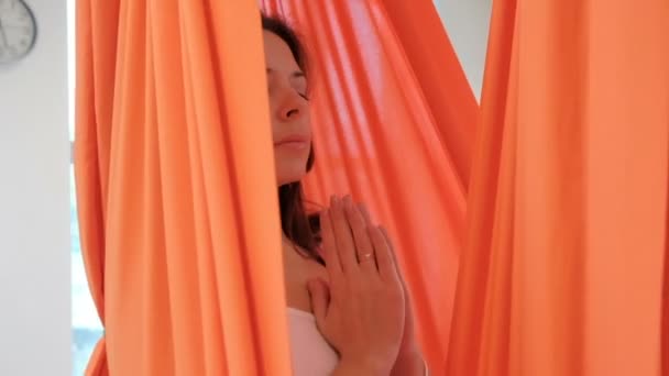 Beautiful brunette swaying in hammock in lotus pose indoors. — Stock Video