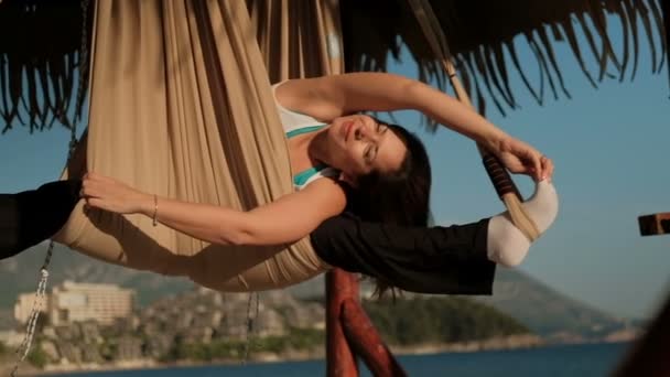 요가의 운동 하는 동안 해변에서 해먹에 스윙 하는 여자 — 비디오