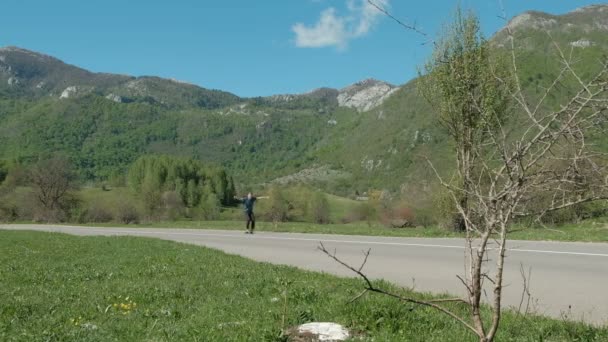 Um homem adulto monta um skate entre as altas montanhas . — Vídeo de Stock