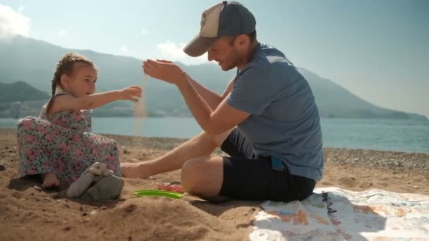 Papa et fille jouent gracieusement sur le bord de la mer par temps ensoleillé . — Video