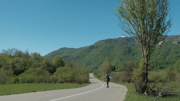 Młody człowiek jazda na longboard na drodze kraju w letni dzień. — Wideo stockowe