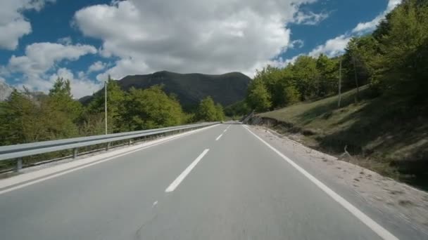 Tráfico en una carretera recta uniforme a las montañas en el verano . — Vídeos de Stock