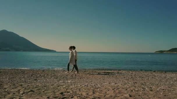 Couple copain détendu prenant petite amie sur les mains tordant sur le bord de la mer marchant sur le rivage de la mer tenant la main en regardant dans la distance . — Video