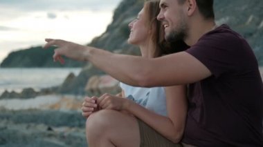 Kucaklama gün batımını izlemek taş kıyıda oturan adam kadın