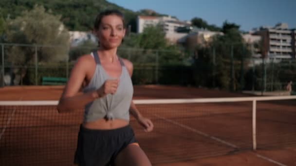 Молода жінка тренується перед тенісним матчем у відкритому дворі . — стокове відео