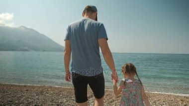 Küçük kız sahil güneşli gün açık havada üzerinde yürüme ile genç adam.